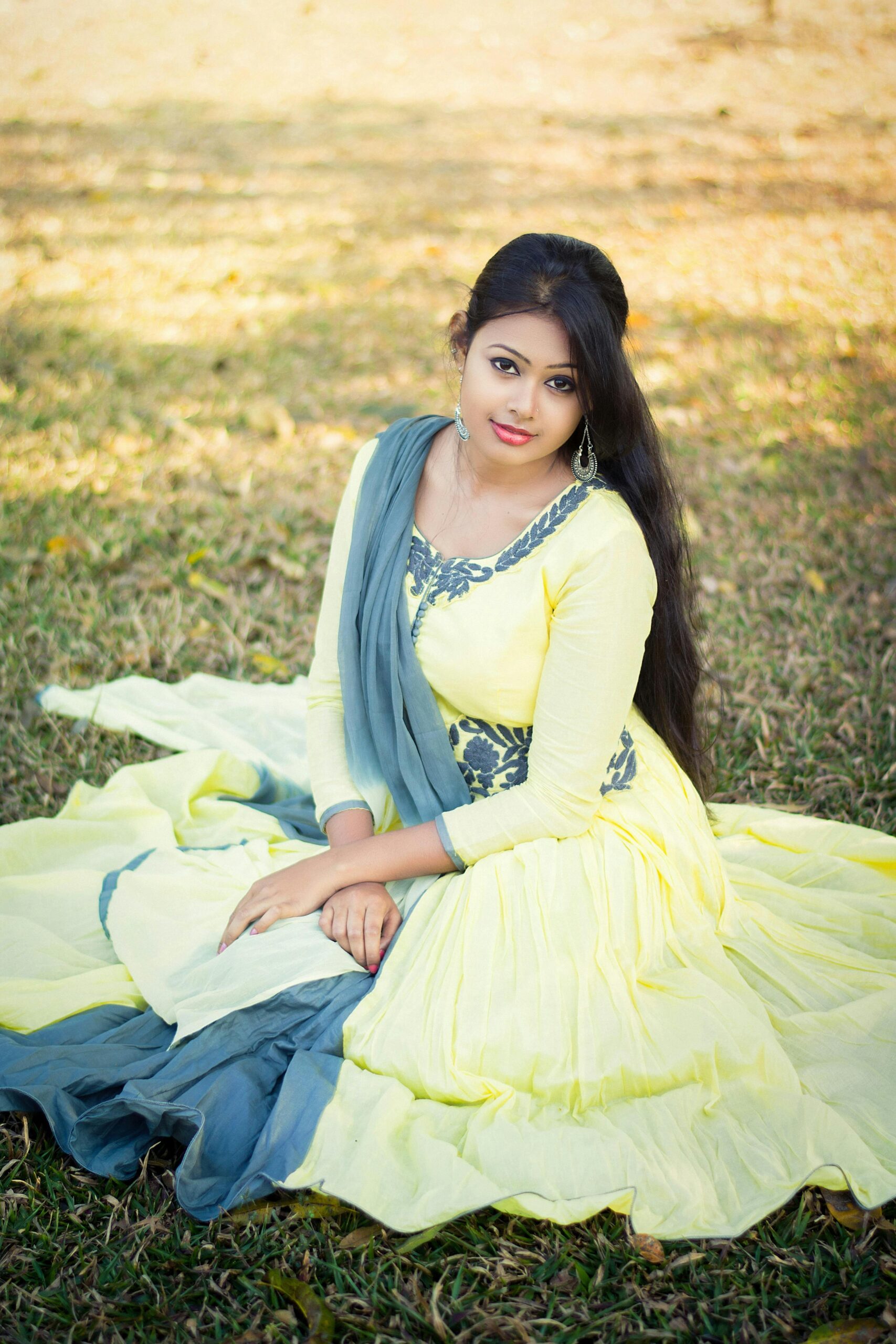 Portrait of a woman in traditional attire, sitting gracefully in a sunny park setting.